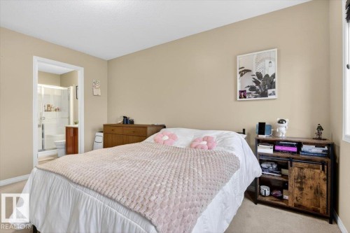 The property features a bedroom with light-colored walls and carpeting, a window providing natural light, and an entryway leading to a bathroom with a shower enclosure and vanity - 1637 Towne Centre Boulevard, Edmonton, AB - Indoor Photo Showing Bedroom