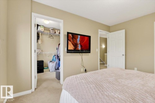 This bedroom features neutral-toned walls and carpeting, a closet with wire shelving, and a white paneled door - 1637 Towne Centre Boulevard, Edmonton, AB - Indoor Photo Showing Bedroom