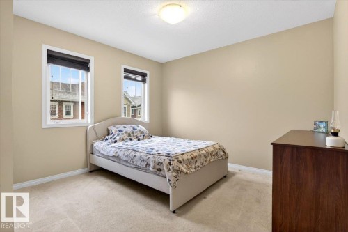 This room features two windows, a light-colored carpet, and walls painted in a neutral tone - 1637 Towne Centre Boulevard, Edmonton, AB - Indoor Photo Showing Bedroom