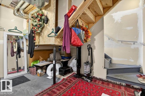 The property features a concrete floor and a wooden staircase with a grey finish, leading to an upper level - 1637 Towne Centre Boulevard, Edmonton, AB - Indoor