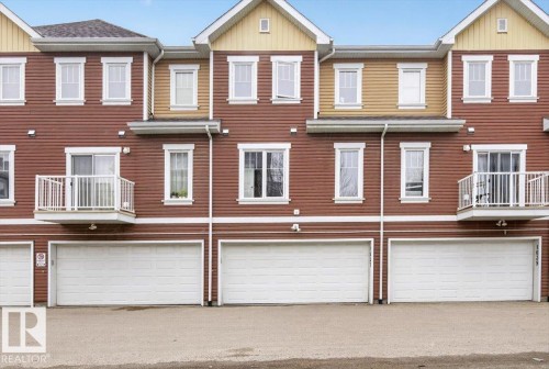 The property features a multi-story exterior with red siding and white trim, individual garage bays, and balconies with white railings - 1637 Towne Centre Boulevard, Edmonton, AB - Outdoor With Facade
