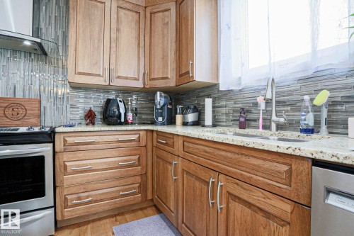 The kitchen features wood cabinetry, a tiled backsplash, and light-colored countertops - 18 Enchanted Way, St. Albert, AB 