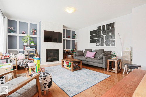 The living room features hardwood flooring, a fireplace, and built-in shelving - 18 Enchanted Way, St. Albert, AB 