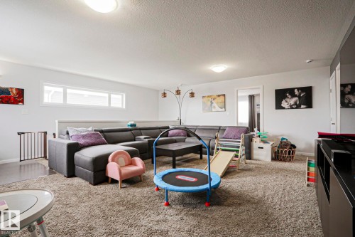 Spacious living area featuring light-colored walls, recessed lighting, and a large window providing natural light - 18 Enchanted Way, St. Albert, AB 