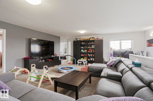Spacious living area featuring neutral-toned carpeting, light-colored walls, and a large window providing natural light - 18 Enchanted Way, St. Albert, AB 