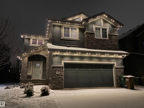 The property features a dark gray exterior with stone accents and a two-car garage - 18 Enchanted Way, St. Albert, AB 