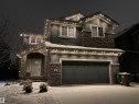 The property features a dark gray exterior with stone accents and a two-car garage - 18 Enchanted Way, St. Albert, AB 