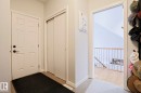 The foyer features a white paneled door with matte black hardware, a closet with sliding paneled doors, and light-colored flooring - 18 Enchanted Way, St. Albert, AB 