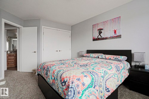 This bedroom features plush grey carpeting, light grey walls, and a convenient closet with white double doors - 18 Enchanted Way, St. Albert, AB 