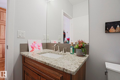 The bathroom features a vanity with a granite countertop, an undermount sink, and a wood cabinet - 18 Enchanted Way, St. Albert, AB 