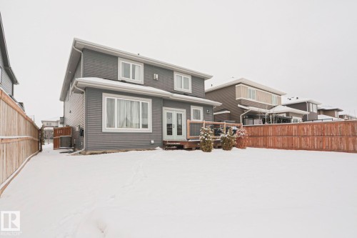 The property features a two-story exterior with horizontal siding, a fenced yard, and a deck with stairs providing outdoor access - 18 Enchanted Way, St. Albert, AB 