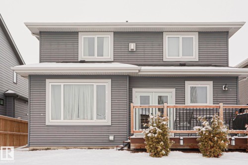 The property features grey horizontal siding, white trim, and a rear deck with a wooden railing - 18 Enchanted Way, St. Albert, AB 