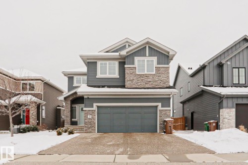 The property features a two-story exterior with grey siding and stone accents, a double garage, and a covered entryway - 18 Enchanted Way, St. Albert, AB 