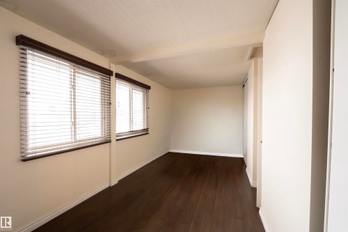 This room features dark wood flooring, light-colored walls, and two windows with blinds - 1728 37 Street, Edmonton, AB - Indoor Photo Showing Other Room
