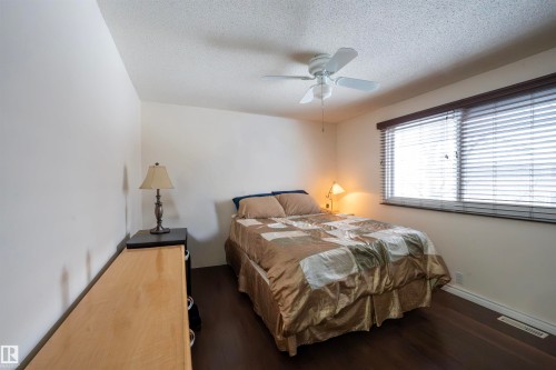 This room features dark wood flooring, a window with horizontal blinds, and a ceiling fan - 1728 37 Street, Edmonton, AB - Indoor Photo Showing Bedroom