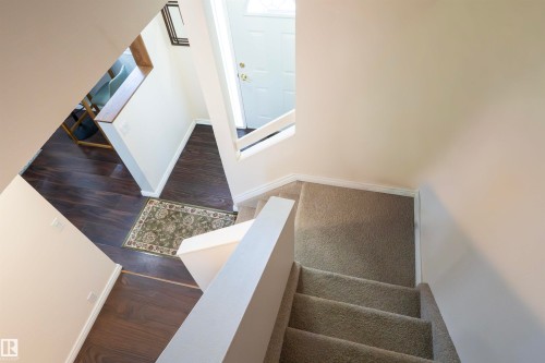 The entryway features dark wood flooring, a white door, and a carpeted staircase with white railings - 1728 37 Street, Edmonton, AB - Indoor Photo Showing Other Room