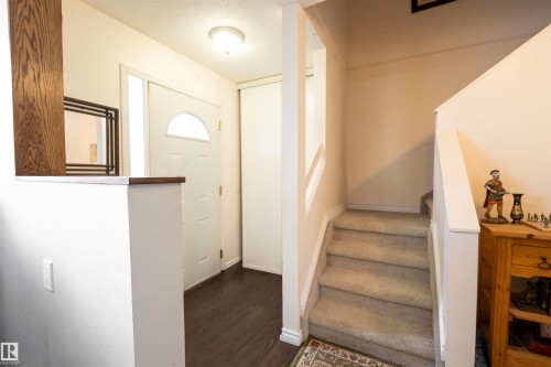 Welcoming entryway featuring dark wood-style flooring, a white front door with an arched window, and a carpeted staircase with white railings - 1728 37 Street, Edmonton, AB - Indoor Photo Showing Other Room