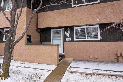 The property features a two-tone exterior with dark vertical siding and light-colored stucco, along with white-framed windows and an accessible front entrance - 1728 37 Street, Edmonton, AB - Outdoor With Exterior