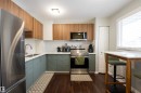 The kitchen features stainless steel appliances, wood-toned upper cabinetry, and contrasting green lower cabinetry - 1728 37 Street, Edmonton, AB  - Indoor Photo Showing Kitchen With Double Sink With Upgraded Kitchen 