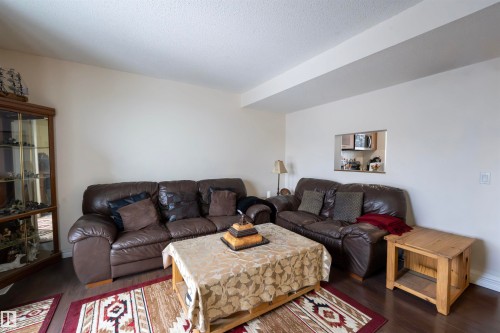 Living area featuring dark flooring, light-colored walls, and a pass-through window to an adjacent space - 1728 37 Street, Edmonton, AB - Indoor Photo Showing Living Room