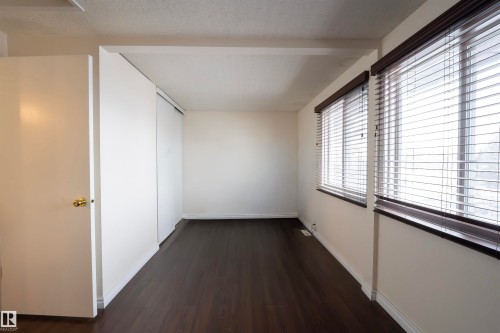 This room features dark flooring, white walls, and windows fitted with horizontal blinds - 1728 37 Street, Edmonton, AB - Indoor Photo Showing Other Room