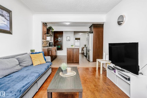 This property features wood flooring in the foreground, with an open archway leading to a tiled area - 6524 112 Street, Edmonton, AB - Indoor Photo Showing Living Room