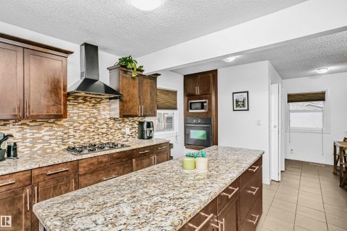 The kitchen features granite countertops, dark wood cabinetry, and a mosaic tile backsplash - 6524 112 Street, Edmonton, AB - Indoor Photo Showing Kitchen With Upgraded Kitchen