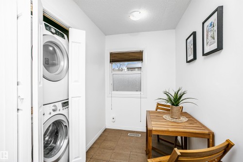 This utility area features a stackable washer and dryer, a window with blinds, and tiled flooring - 6524 112 Street, Edmonton, AB - Indoor Photo Showing Laundry Room