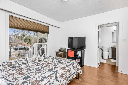 The property features a room with wood flooring and a large window, offering views of the exterior - 6524 112 Street, Edmonton, AB - Indoor Photo Showing Bedroom
