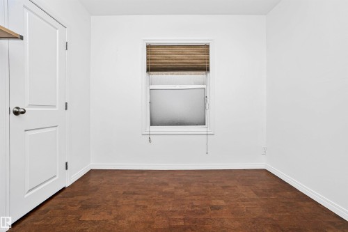 This room features rich brown flooring, crisp white walls, and a window with blinds providing natural light - 6524 112 Street, Edmonton, AB - Indoor Photo Showing Other Room