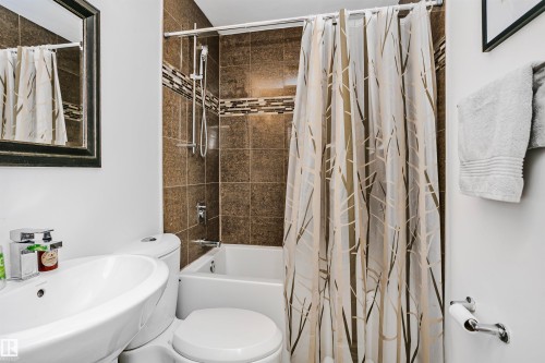 This bathroom features a white bathtub and toilet, complemented by a white vanity with an undermount sink - 6524 112 Street, Edmonton, AB - Indoor Photo Showing Bathroom