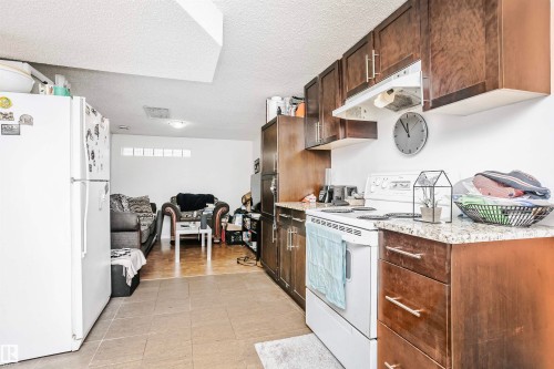 The property features a kitchen with dark wood cabinetry, a white stove, and granite-style countertops - 6524 112 Street, Edmonton, AB - Indoor Photo Showing Kitchen