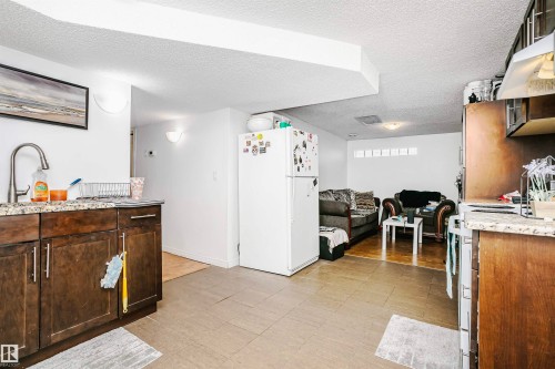The property features a kitchen area with dark wood cabinetry, granite countertops, and a stainless steel sink with a gooseneck faucet - 6524 112 Street, Edmonton, AB - Indoor Photo Showing Kitchen