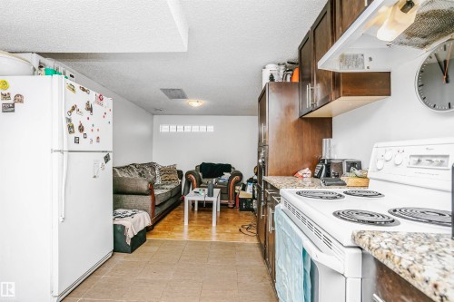 The kitchen features white appliances, including a refrigerator and an electric range, complemented by granite countertops and dark wood cabinetry - 6524 112 Street, Edmonton, AB - Indoor Photo Showing Kitchen