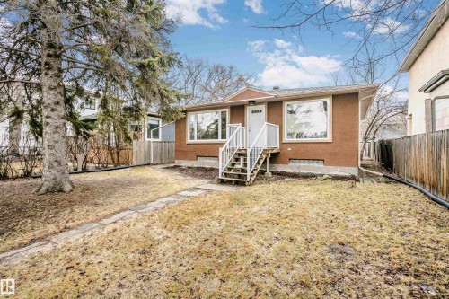 The property features a brown stucco exterior with a white front door and white exterior stairs - 6524 112 Street, Edmonton, AB - Outdoor