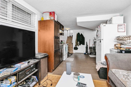 This open-concept living area features tile flooring, a window with blinds, and a staircase - 6524 112 Street, Edmonton, AB - Indoor