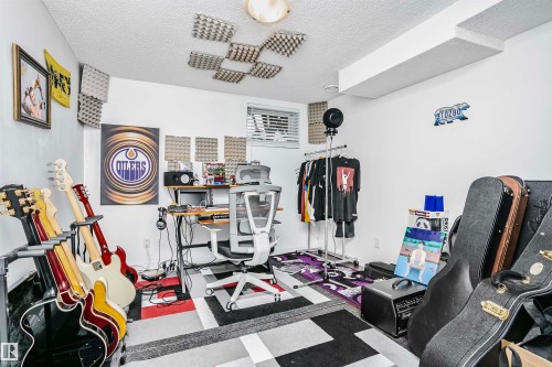 This room features white walls, a ceiling with acoustic paneling, and a distinct geometric patterned area rug - 6524 112 Street, Edmonton, AB - Indoor