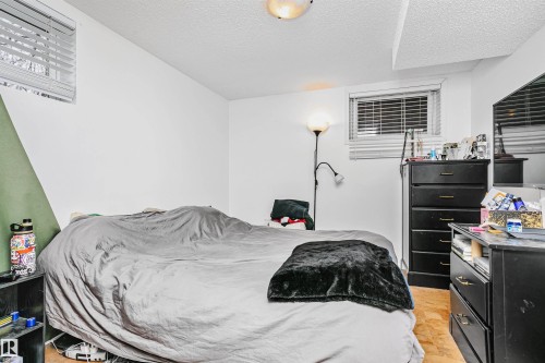 This bedroom features white walls, a textured ceiling, and two windows providing natural light - 6524 112 Street, Edmonton, AB - Indoor Photo Showing Bedroom