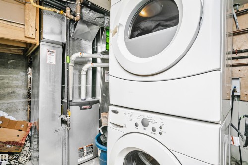 Dedicated laundry area featuring a white stacked washer and dryer, alongside a furnace and water heater - 6524 112 Street, Edmonton, AB - Indoor Photo Showing Laundry Room