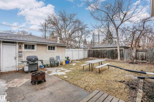 The property features a private yard with a concrete patio area, a lawn, and mature trees - 6524 112 Street, Edmonton, AB - Outdoor