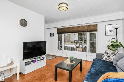 Living area featuring hardwood flooring, a large window with blinds, and a ceiling light fixture - 6524 112 Street, Edmonton, AB - Indoor Photo Showing Living Room