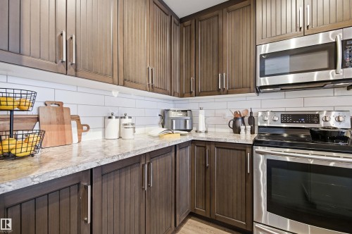 The kitchen features wood cabinetry, light-colored countertops, a white subway tile backsplash, and stainless steel appliances - 678 Secord Boulevard, Edmonton, AB - Indoor Photo Showing Kitchen