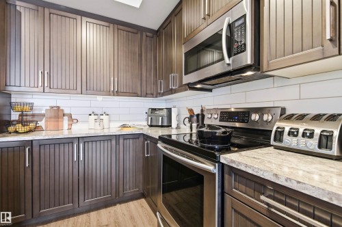 The kitchen features dark wood cabinetry, white subway tile backsplash, and light-colored countertops - 678 Secord Boulevard, Edmonton, AB - Indoor Photo Showing Kitchen With Upgraded Kitchen