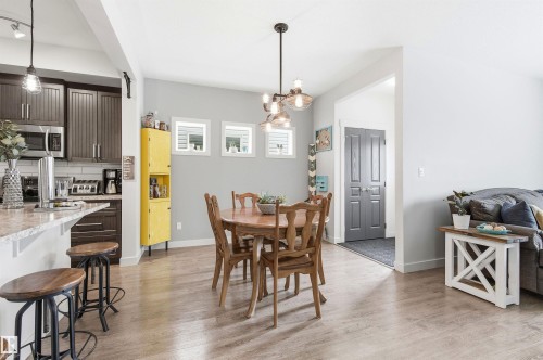 Well-appointed kitchen featuring dark wood cabinetry, stainless steel appliances, and a granite countertop breakfast bar with seating - 678 Secord Boulevard, Edmonton, AB - Indoor Photo Showing Dining Room