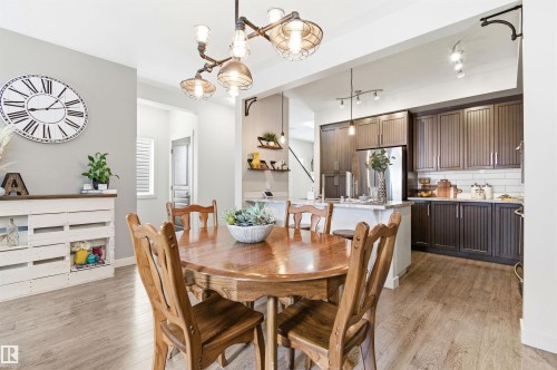 Dining area with hardwood style flooring and an industrial-style chandelier - 678 Secord Boulevard, Edmonton, AB - Indoor Photo Showing Dining Room