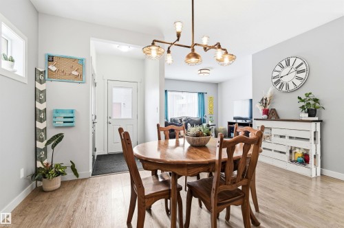 Dining area featuring a wooden table with chairs, a decorative chandelier, and light-colored flooring - 678 Secord Boulevard, Edmonton, AB - Indoor Photo Showing Dining Room