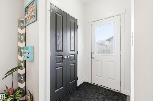The entryway features a white door with a window and a dark-colored closet - 678 Secord Boulevard, Edmonton, AB - Indoor Photo Showing Other Room