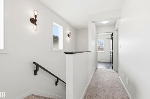 Bright hallway featuring white walls, carpeting, and modern wall sconces - 678 Secord Boulevard, Edmonton, AB - Indoor Photo Showing Other Room