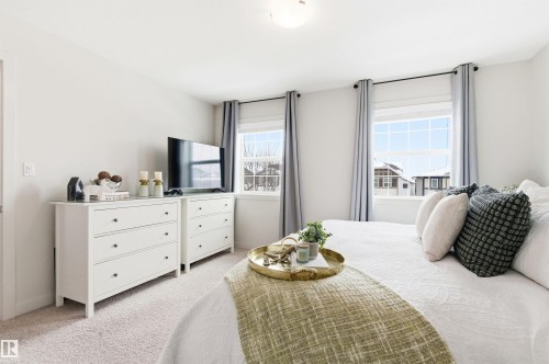 The property features light colored walls, carpeted floors, and windows with window treatments - 678 Secord Boulevard, Edmonton, AB - Indoor Photo Showing Bedroom