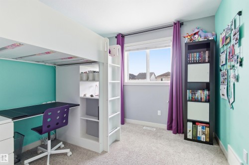 This room features a window with a view of houses, light-colored carpeting, and a built-in desk with shelving - 678 Secord Boulevard, Edmonton, AB - Indoor